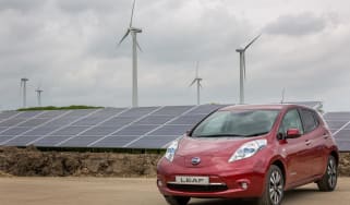 EV parked next to solar and wind farm