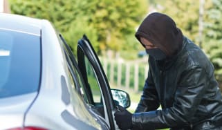 Man wearing a hoodie stealing a car 