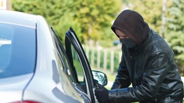 Man wearing a hoodie stealing a car 